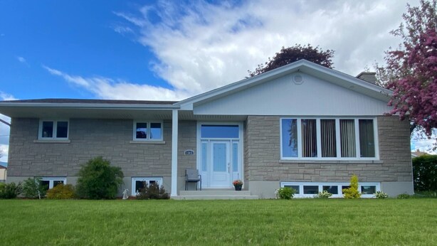 A two-story house with a front porch, a garage, and a well-maintained lawn. - Room-vermaurel Sweet Lodge (Bathurst)