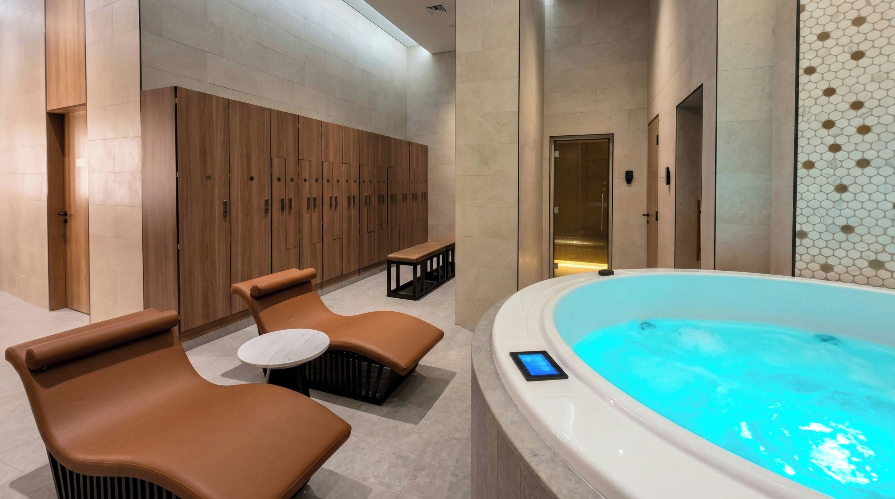 A modern spa area with a hot tub, leather lounge chairs, and a wooden locker room.