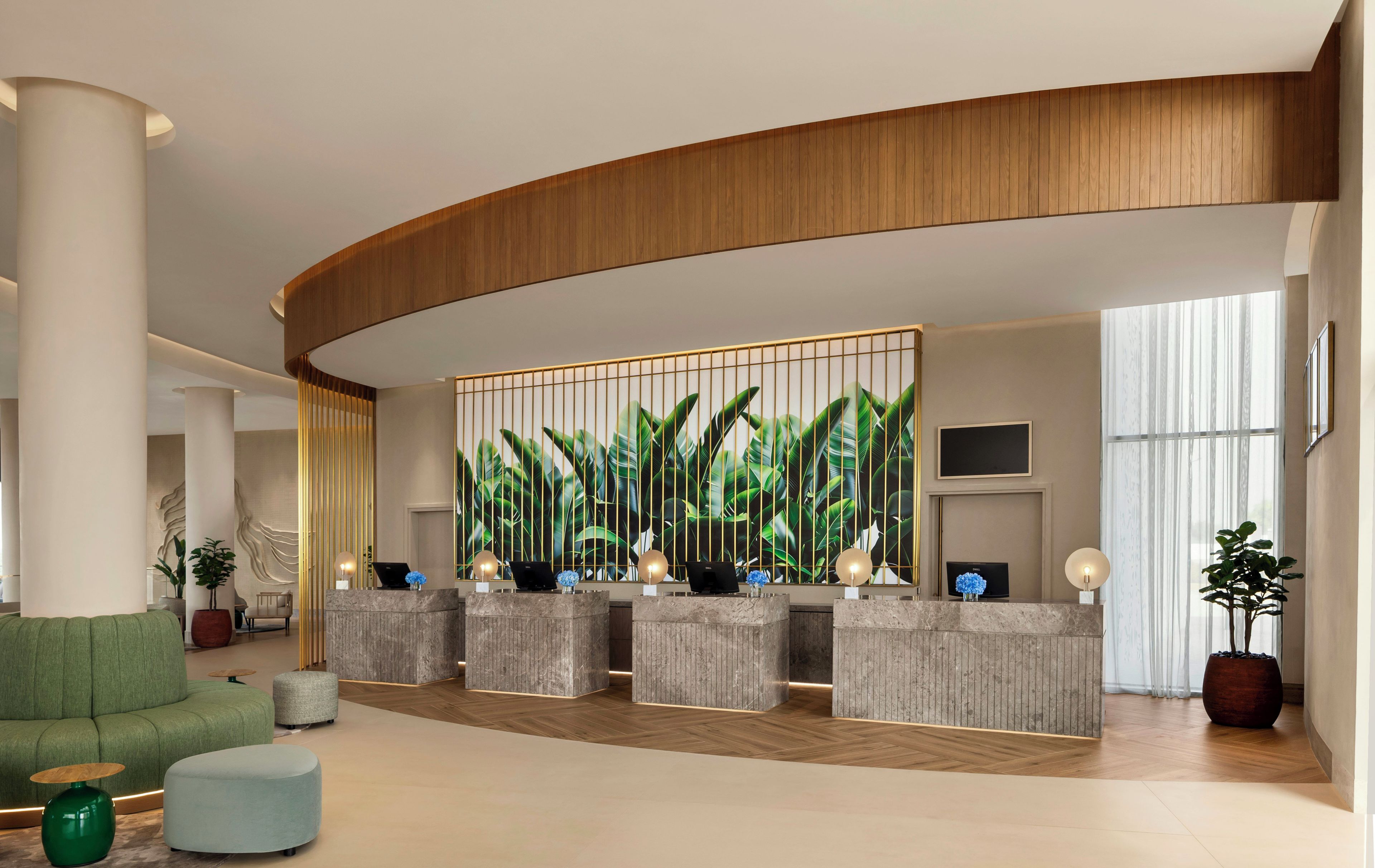 Un área de recepción moderna con techo de madera curvada, un mostrador de recepción con decoración de plantas y un sofá verde.