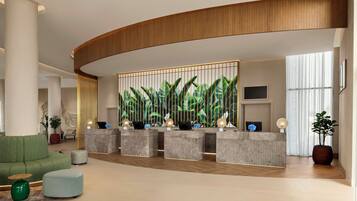 Un área de recepción moderna con techo de madera curvada, un mostrador de recepción con decoración de plantas y un sofá verde.