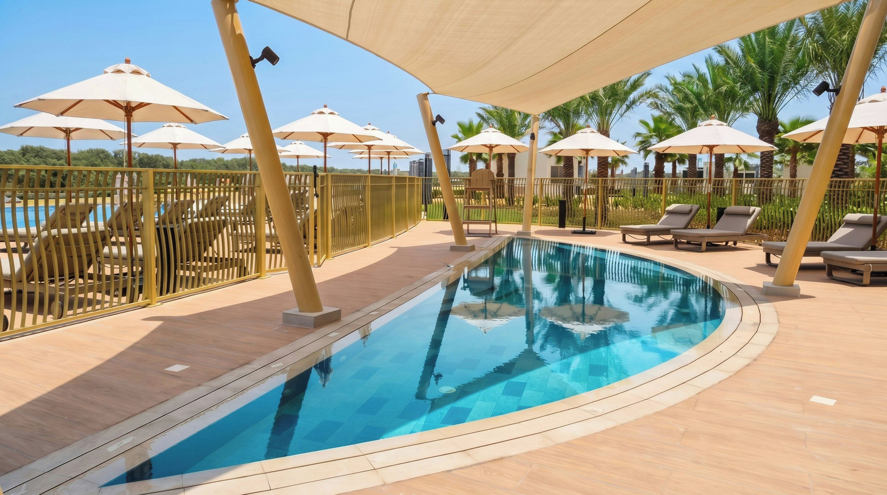 A swimming pool with sun umbrellas, lounge chairs, and a fenced area.
