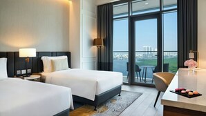 A hotel room with two beds, a desk, a chair, a view of the city, and a balcony. - Rotana Ras Al Khaimah - The Mangroves (Ras Al Khaimah)