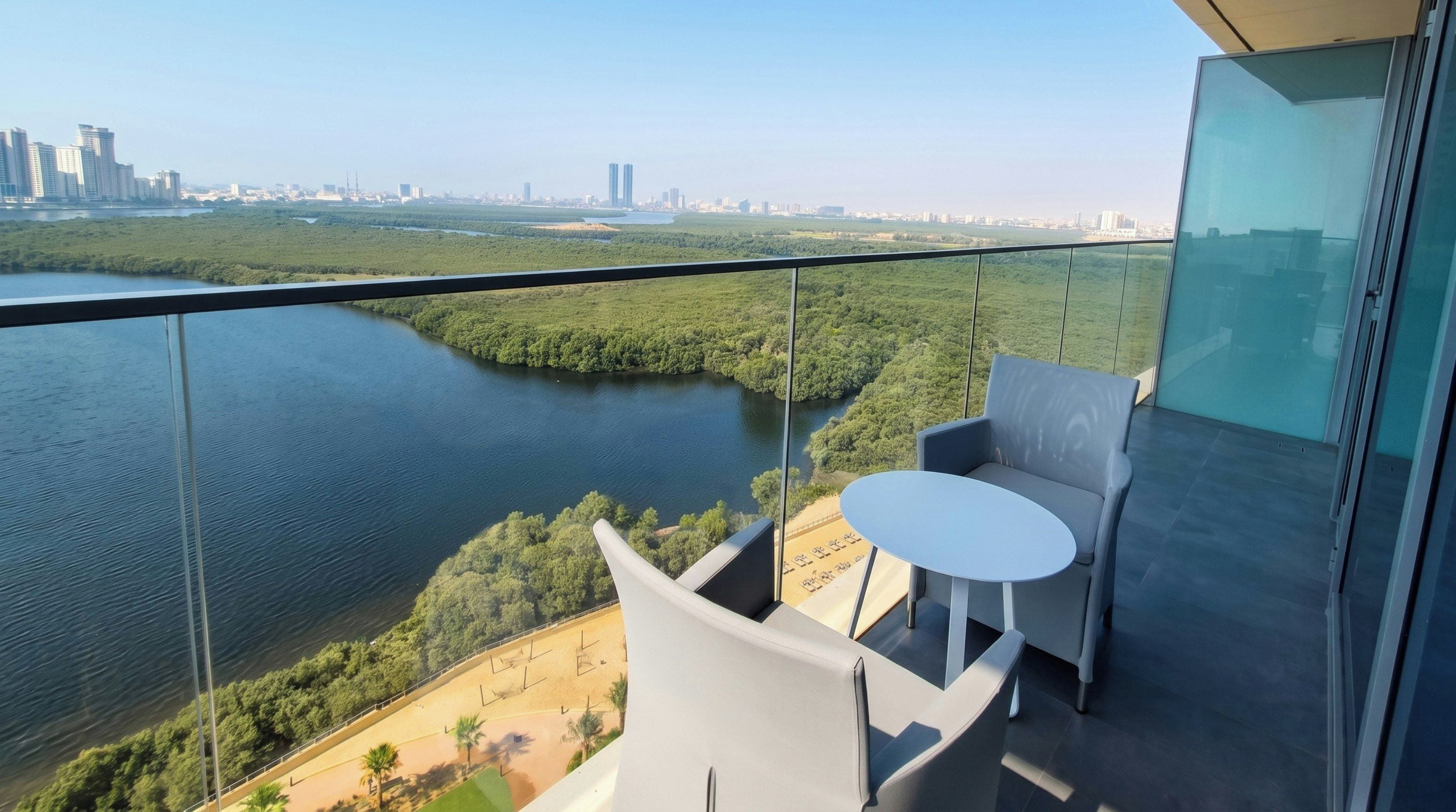 Un balcón con barandilla de vidrio que da a un río y un paisaje urbano.