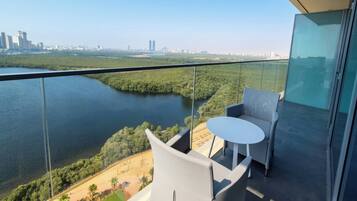 Un balcón con barandilla de vidrio que da a un río y un paisaje urbano.