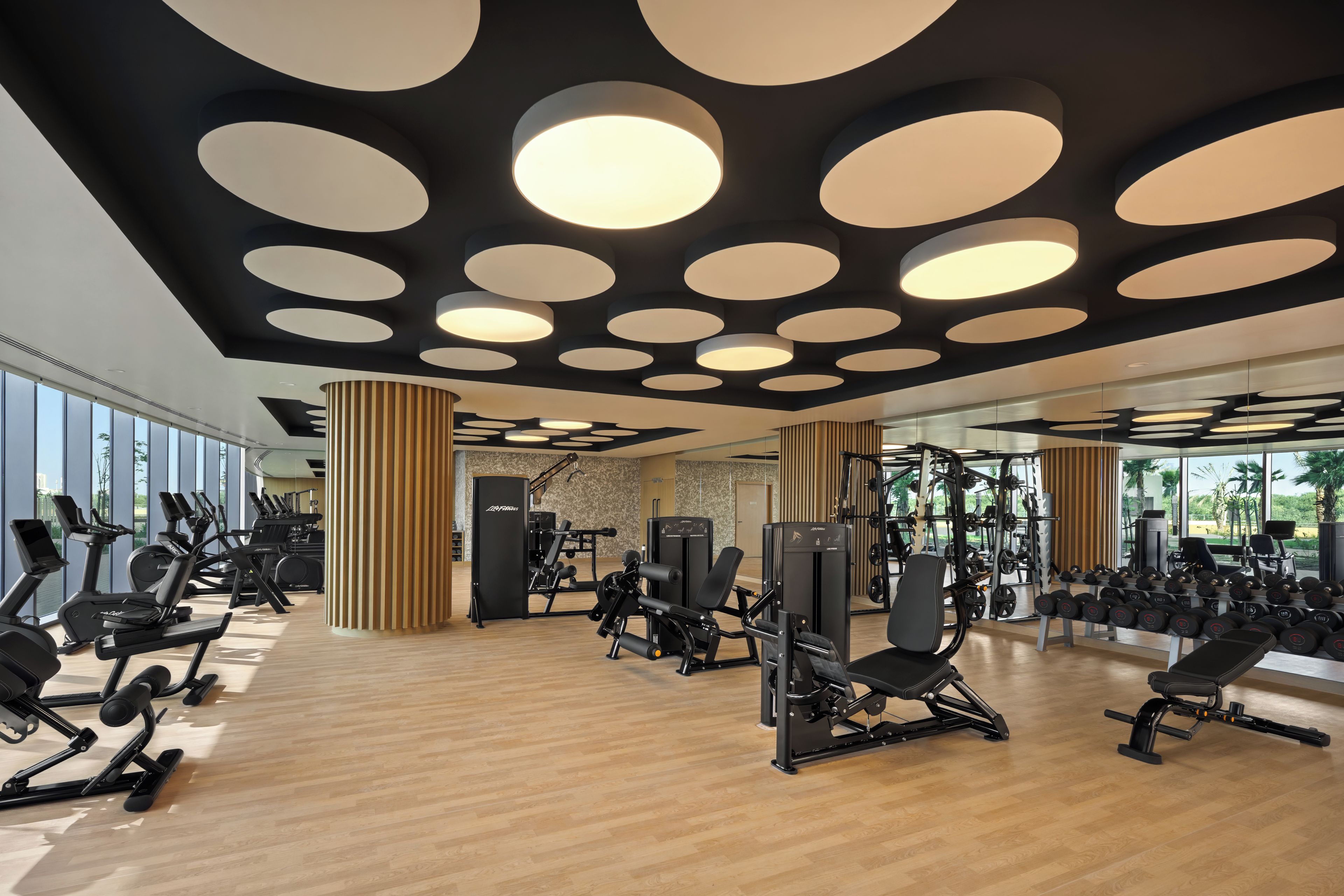 Un gimnasio con equipo de ejercicio, ventanas amplias y un diseño moderno de techo.