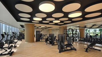 Un gimnasio con equipo de ejercicio, ventanas amplias y un diseño moderno de techo.