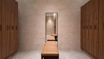 Un pasillo con taquillas de madera, un banco y un espejo que refleja una habitación.