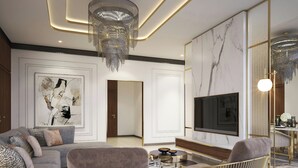 A modern living room with a sofa, armchairs, a coffee table, a TV, and a chandelier. - Rotana Ras Al Khaimah - The Mangroves (Ras Al Khaimah)