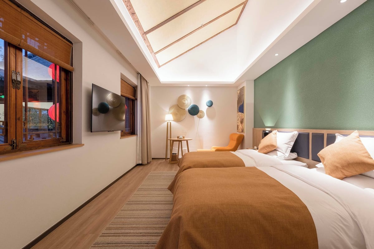 Habitación de hotel moderna con tragaluz, cama con ropa de cama marrón, una silla y decoración en la pared.