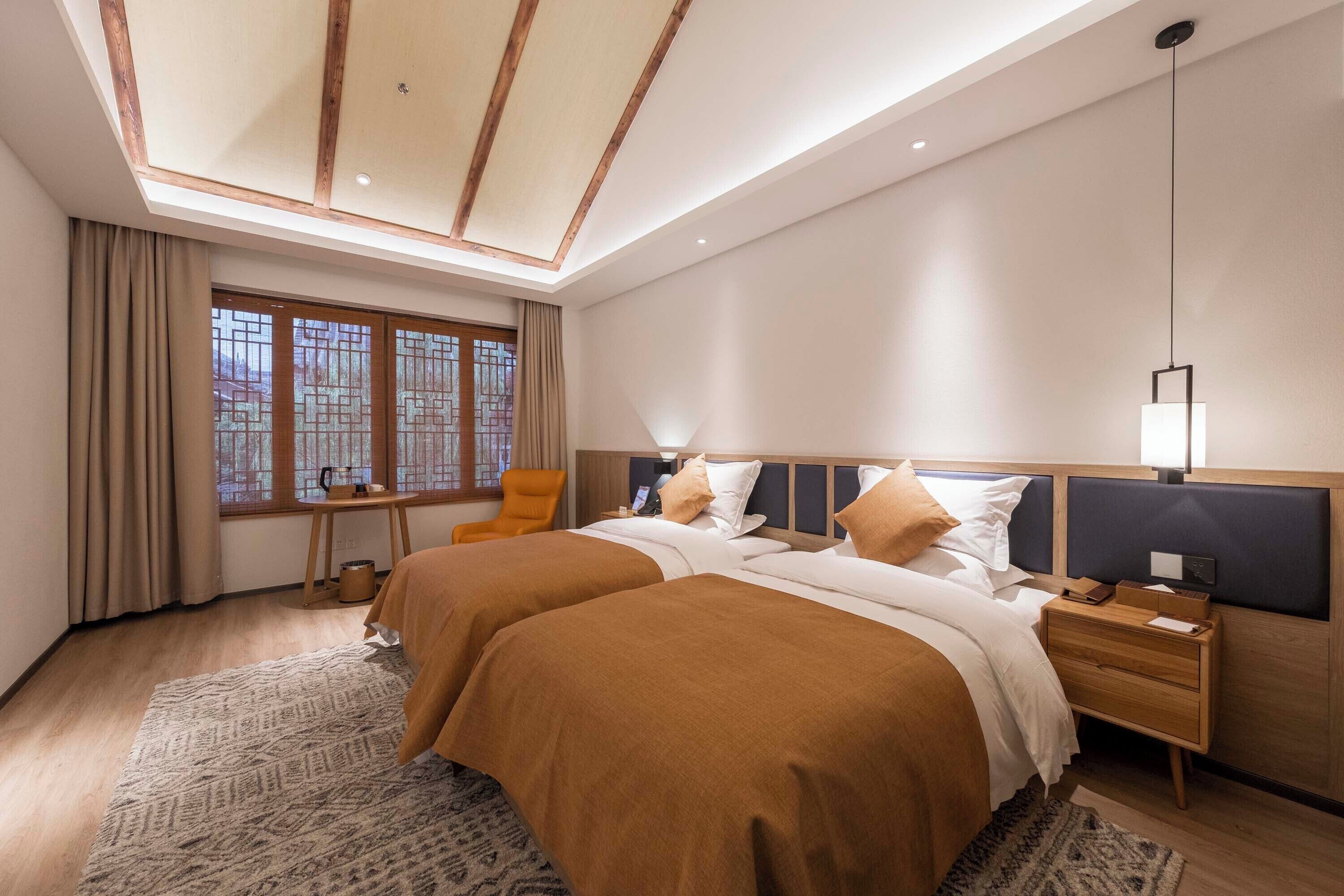 Une chambre d’hôtel moderne avec un grand lit, une table de chevet, une commode, une fenêtre avec des rideaux et une lucarne.