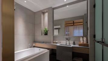 Un baño moderno con bañera, lavamanos y un espejo grande.