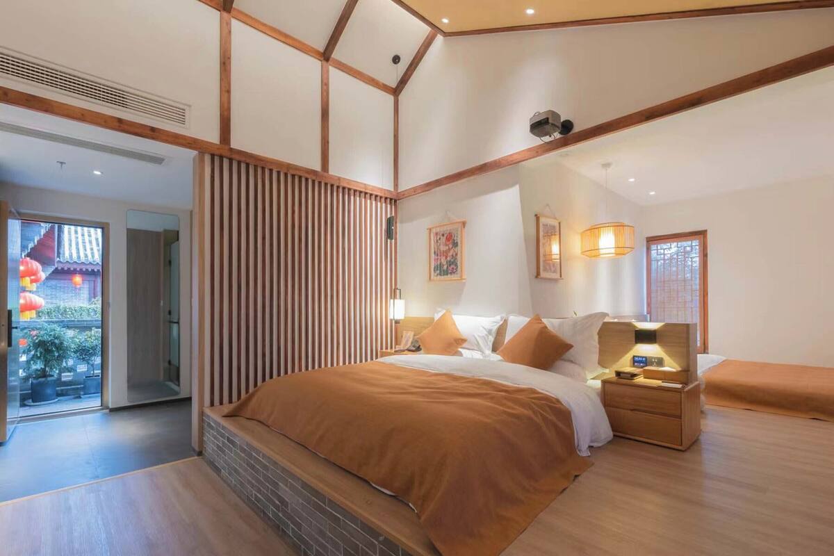 Un dormitorio moderno con una cama grande, mesitas de noche, un cabecero de madera y una puerta corredera que da a un balcón.