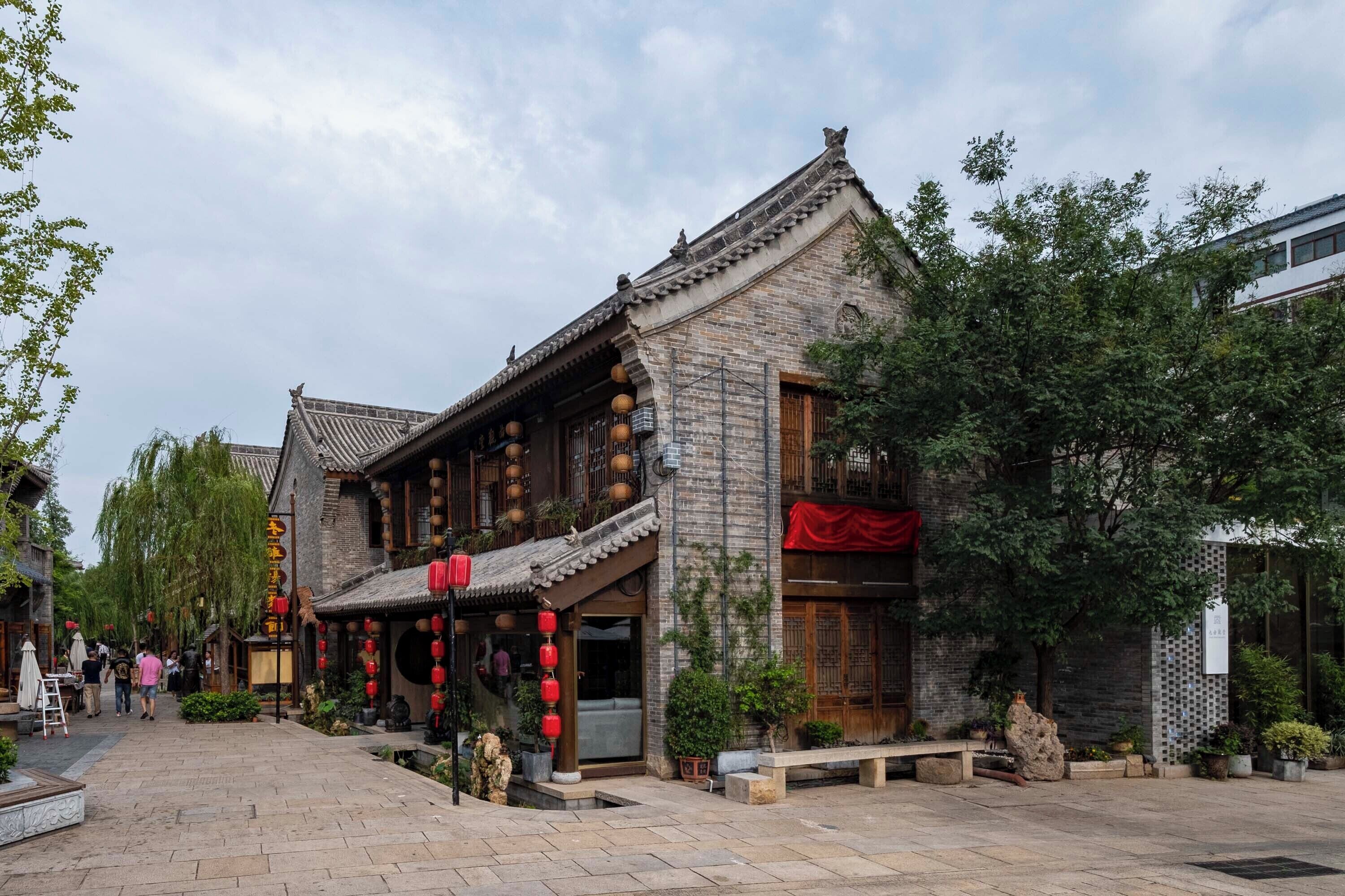 A traditional building with a tiled roof, wooden doors, and red lanterns.