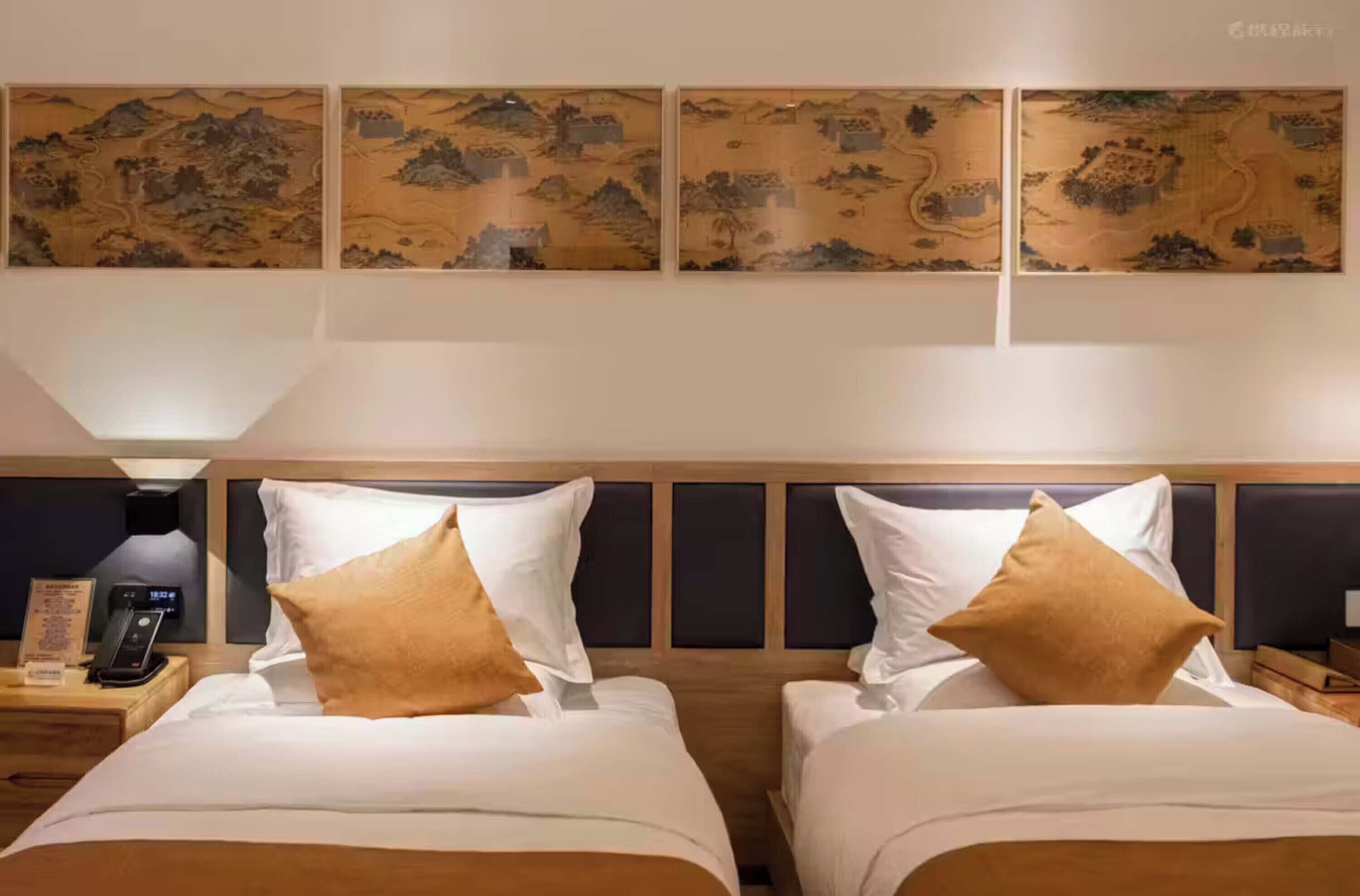 Habitación de hotel con dos camas, una mesita de noche con teléfono y decoración en la pared.