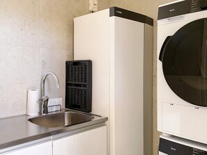A kitchen with a stainless steel sink, a black ventilation unit, and a white appliance with a black top. - 5 Star Holiday Home in Gotlands Tofta (Gotlands Tofta)