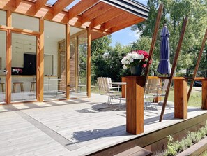 A wooden deck with outdoor furniture, a glass door entrance, and a flower arrangement. - 5 Star Holiday Home in Gotlands Tofta (Gotlands Tofta)