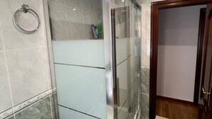 Un baño moderno con cabina de ducha de vidrio, un aro para toallas y suelo de baldosas.