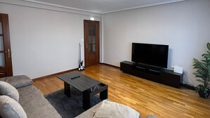 Una sala moderna con un sofá modular, una mesa de centro, un televisor de pantalla plana y una lámpara de techo.