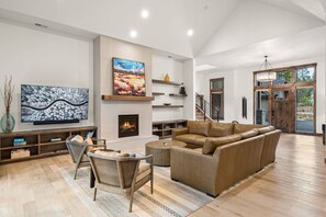 A spacious living room with a fireplace, a large TV, and a modern sofa.