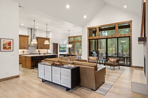 A spacious living area with a large sofa, a dining table, and a kitchen in the background.