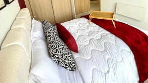 Une chambre à coucher comprenant un lit, une armoire en bois, une table de chevet et une œuvre d’art accrochée au mur.