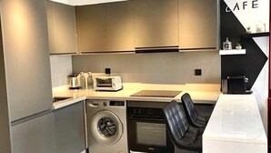 Une cuisine compacte dotée d’appareils électroménagers modernes, d’un four encastré et d’une machine à café.