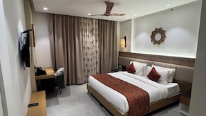 A modern hotel room with a large bed, a desk, a chair, and a television. - Divine OAK Stay  (Pildi)