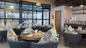 A restaurant with round tables, wicker chairs, and a patterned floor. - Divine OAK Stay  (Pildi)