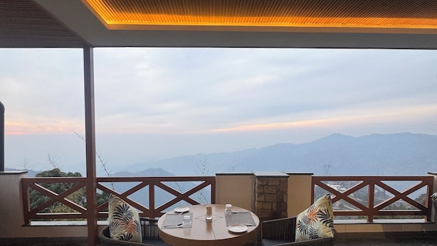 A round table with four chairs and a candle, set on a balcony with a view of mountains. - Divine OAK Stay  (Pildi)