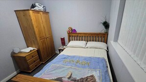 A bedroom with a bed featuring a Harry Potter themed bedspread, a wooden wardrobe, a nightstand with a lamp, and a window with blinds. - Room-eco-cottage Manchester (Manchester)
