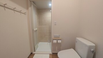 Un baño pequeño y moderno con ducha, inodoro y un lavamanos.