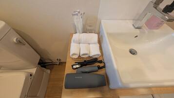 Un bagno con lavandino, porta asciugamani, un contenitore di vetro e asciugacapelli sul ripiano.