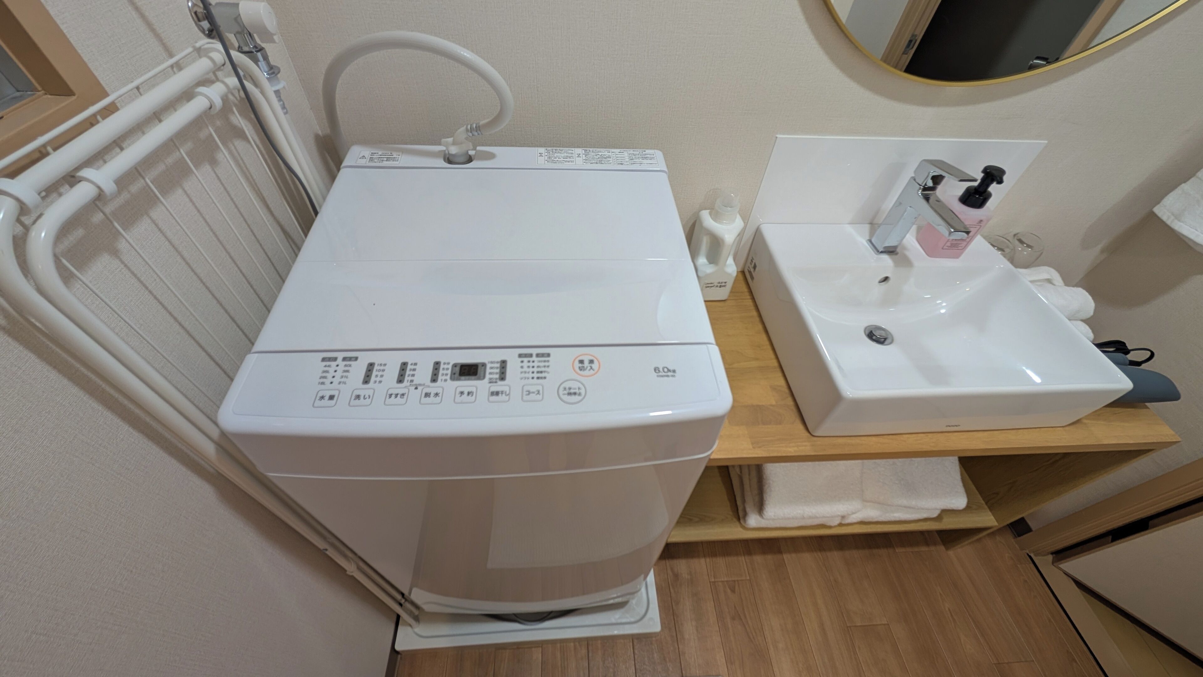 A compact bathroom with a white washing machine, a sink, and a mirror.