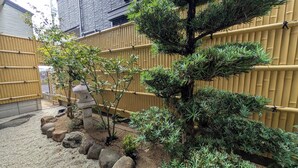 A traditional Japanese garden with a bamboo fence, a stone lantern, and various shrubs. - Dream Stays SORA (Izumisano)