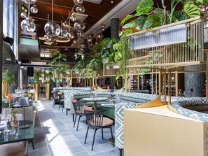 A restaurant with tiered seating, hanging spherical light fixtures, and lush indoor plants. - Explore City Charm from This Modern Rooms Near Landmarks - 2 Units (Rotterdam)