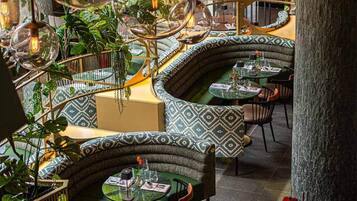 Een restaurant met gebogen zitplaatsen, hangende glazen bollen en kamerplanten.