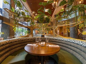 Un restaurant doté d’une table ronde, de sièges rembourrés et de plantes suspendues.