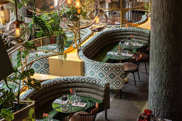 Unwind in plush booth seating beneath glowing glass pendants.