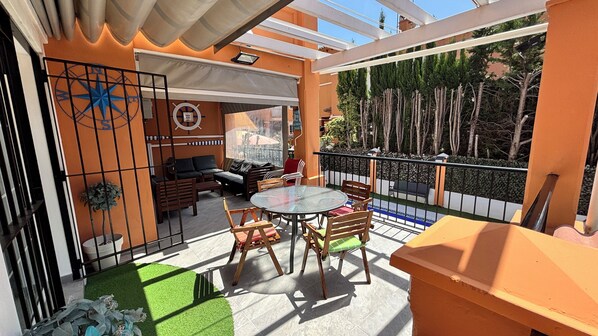 A balcony with a glass table, chairs, and a sofa.