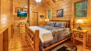 A cozy wooden cabin bedroom with a bed, a television, and a ceiling fan. - Finding Bigfoot 2 Bedroom Cabin (Sevierville)