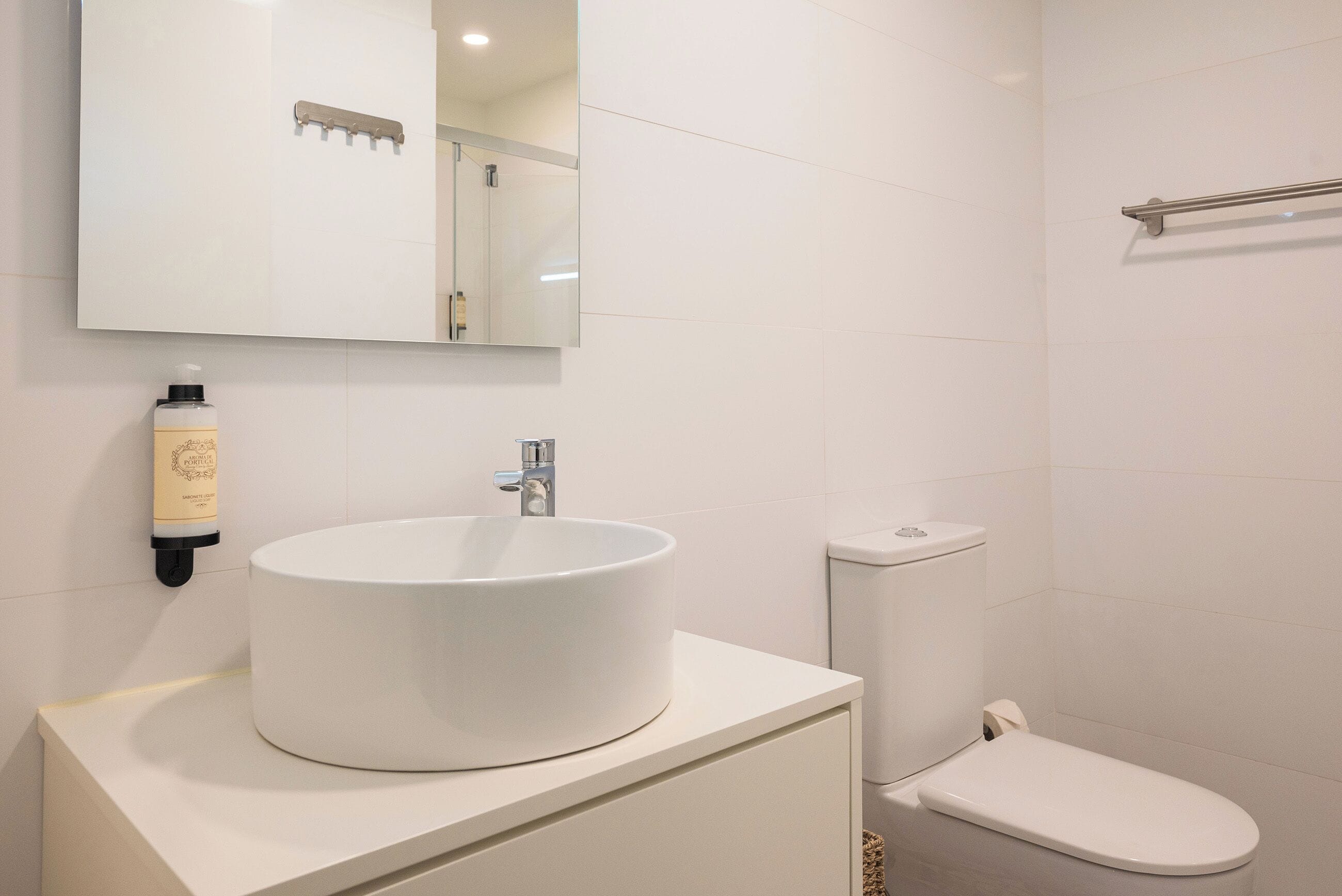 A bathroom with a white sink, a toilet, and a mirror.