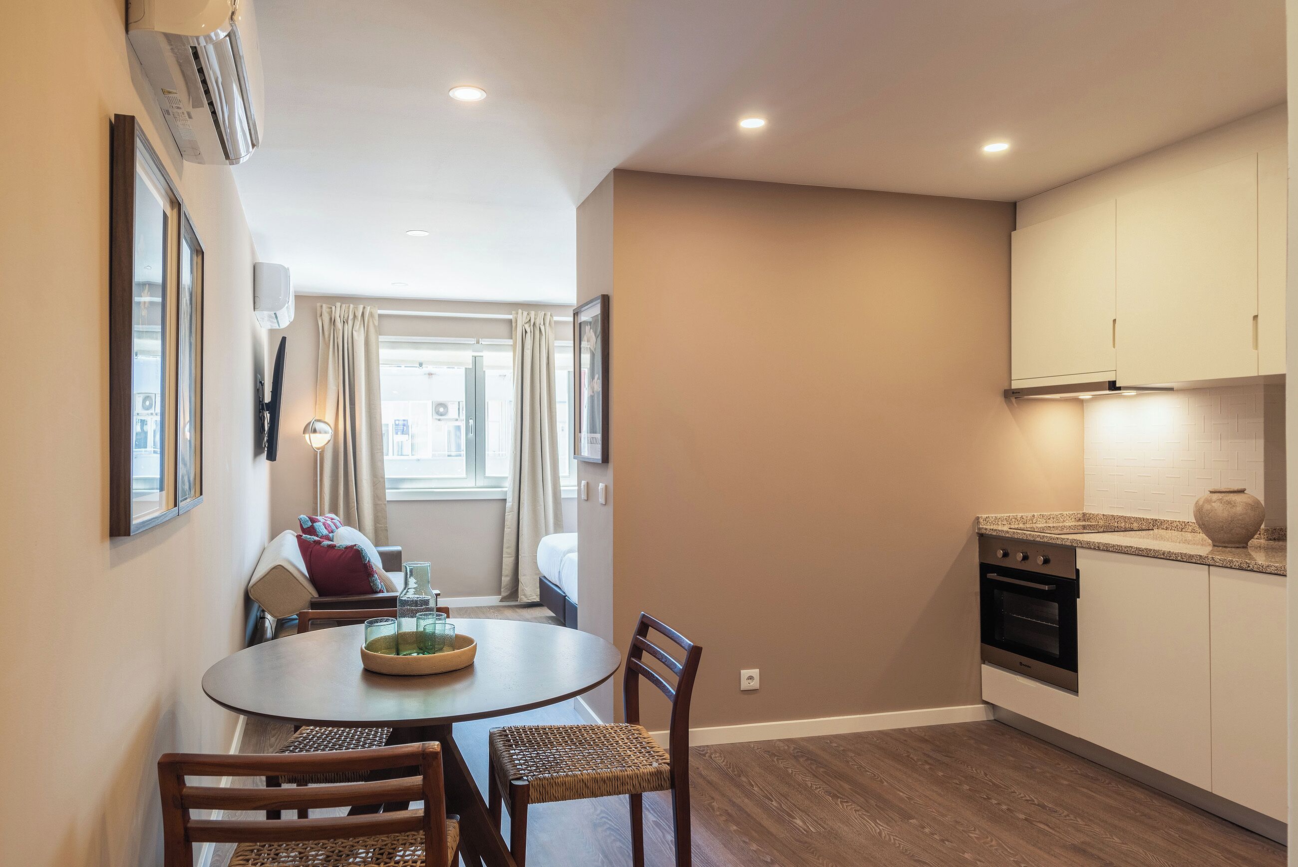 A compact kitchen with a dining area, featuring a round table, chairs, and a built-in oven.