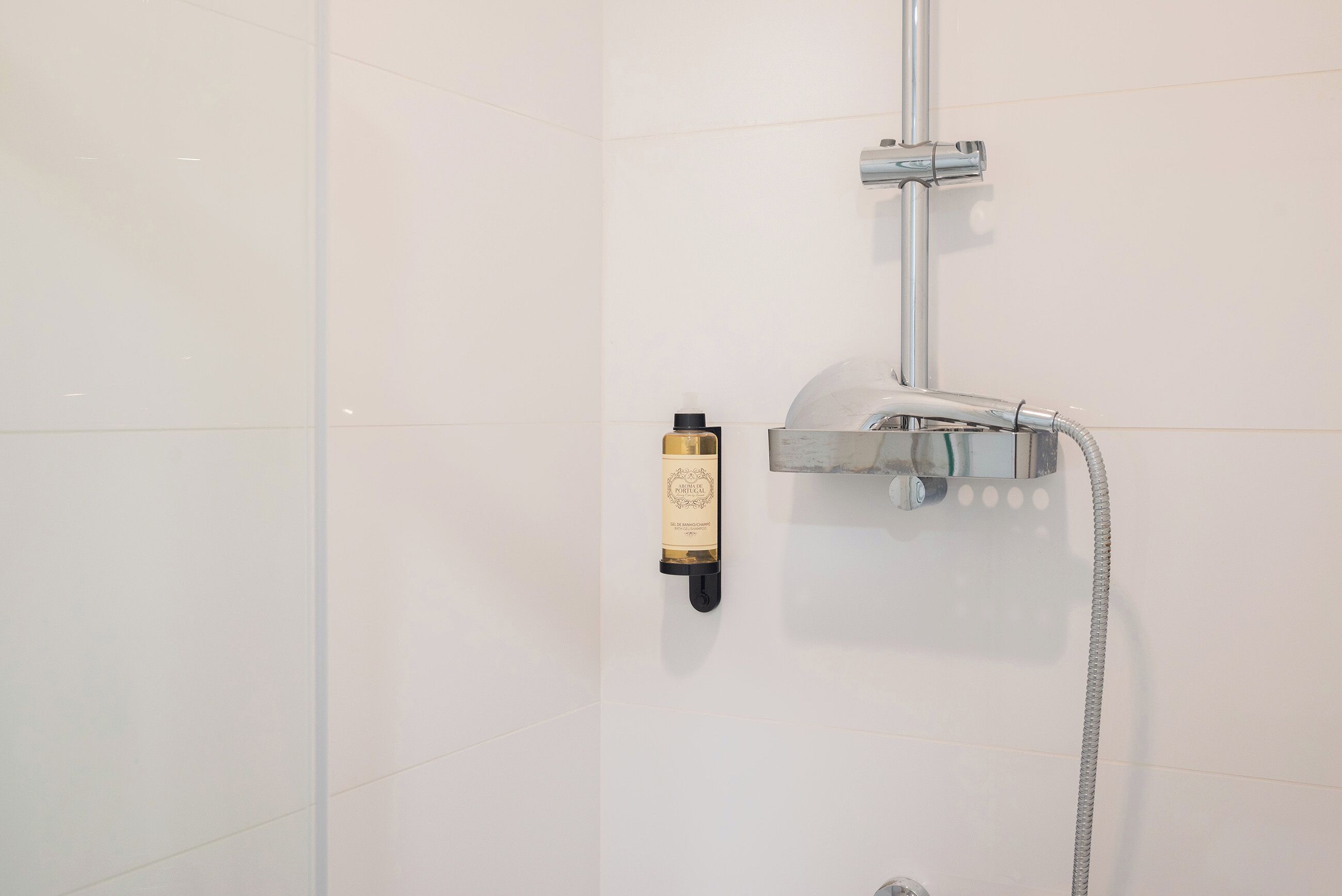 A shower with a handheld showerhead and a handheld soap dispenser.