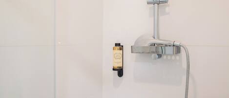 A shower with a handheld showerhead and a handheld soap dispenser.