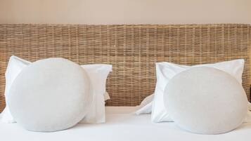 Una cama con dos almohadillas redondas y un cabecero tejido.