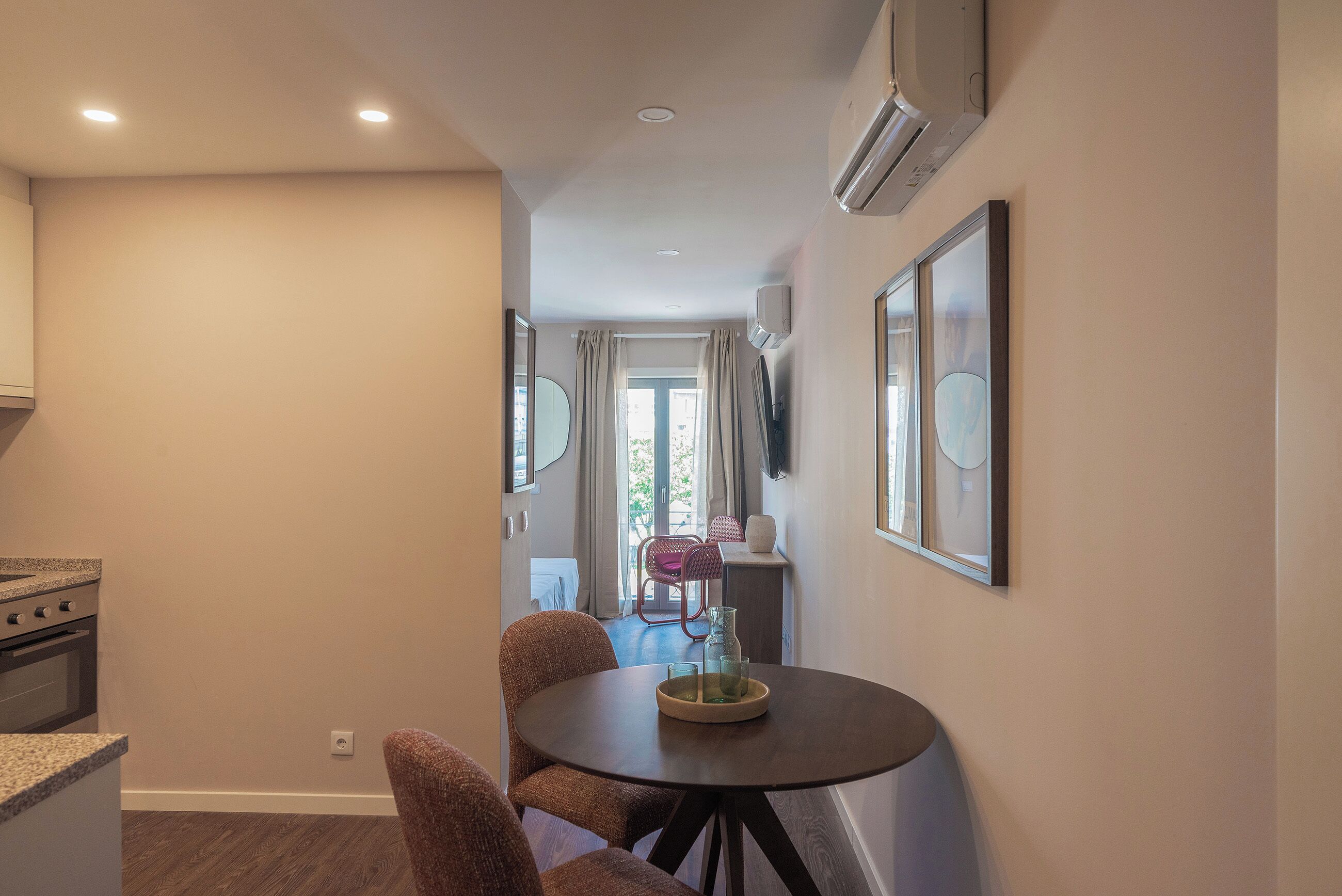 A modern kitchen with a built-in oven and a dining area with a round table and wicker chairs.