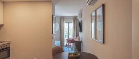 A modern kitchen with a built-in oven and a dining area with a round table and wicker chairs.