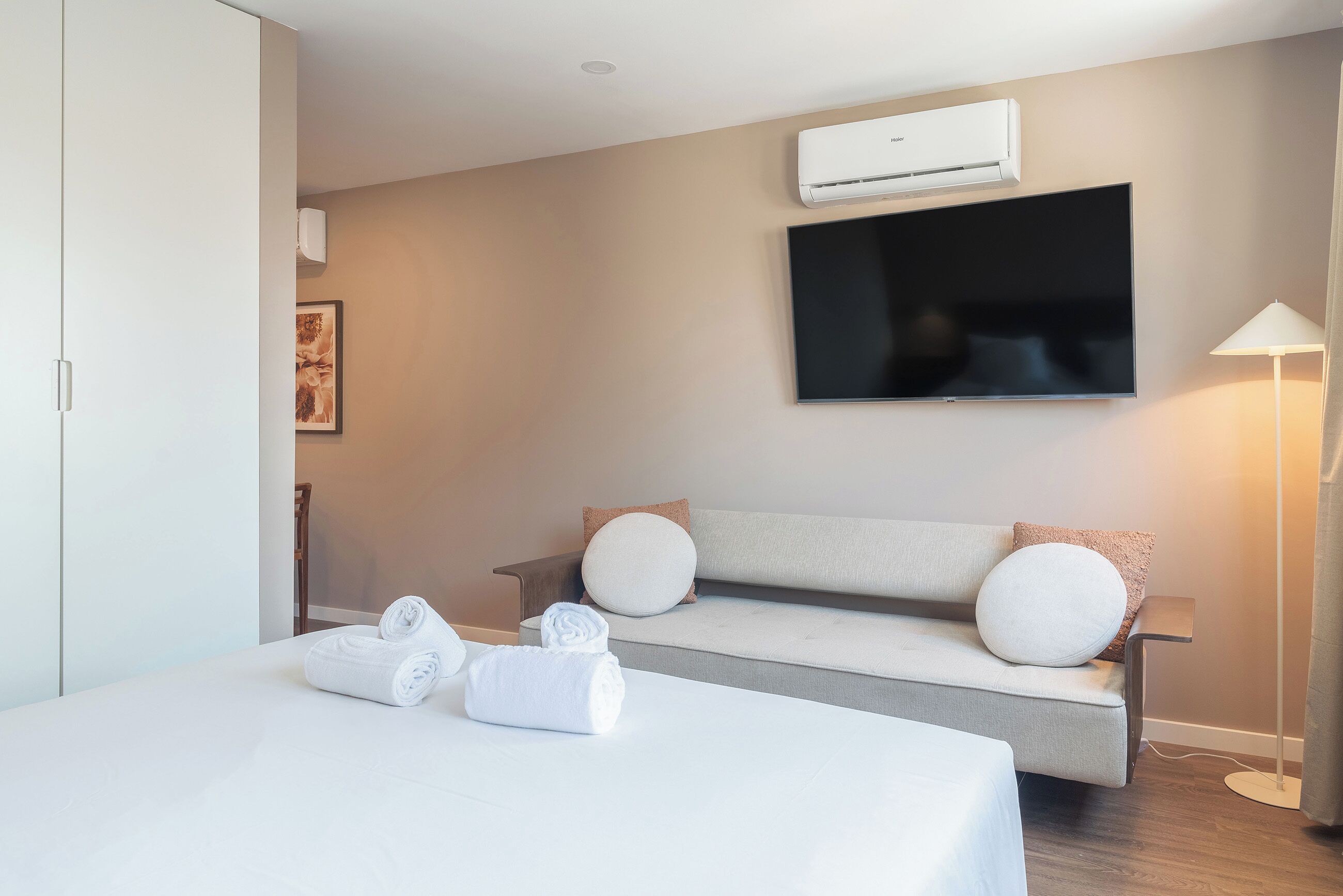 Una habitación de hotel moderna con una cama, un sofá, un televisor de pantalla plana y un equipo de aire acondicionado.