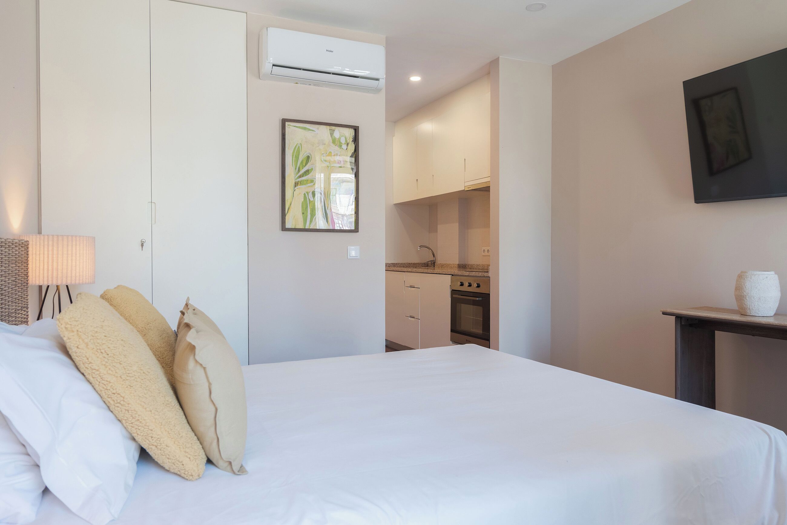 Une chambre à coucher avec un lit, des oreillers, une lampe de chevet et un climatiseur fixé au mur.