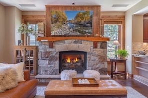 A stone fireplace with a fire, a wooden mantel, and a painting above it. - New Listing! Village at Northstar Residence - Big Horn 412 (Truckee)